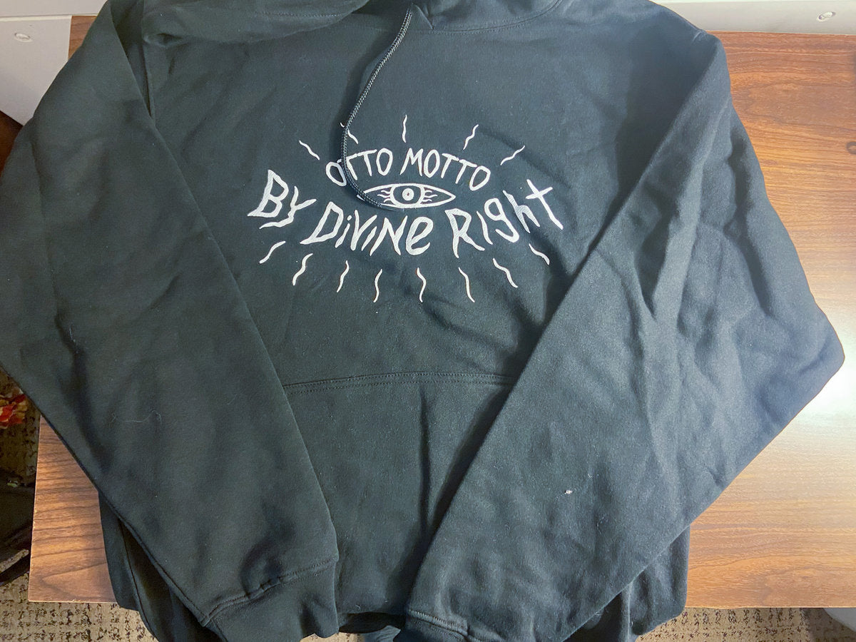 Black by divine right hoodie with white text on a wooden surface